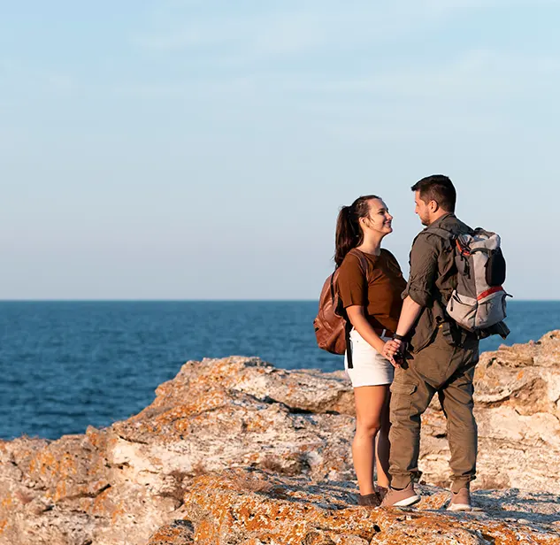 couple se tenant les mains dans un falaise de bonifacio avec la mer en fond