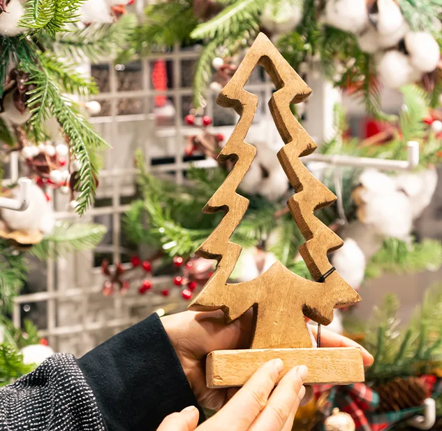 hands holding a wooden christmas tree shaped decoration