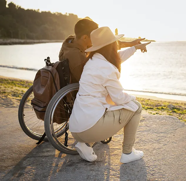 couple looking at the sea on a sandy accessible beach in sardinia, him on a wheelchair