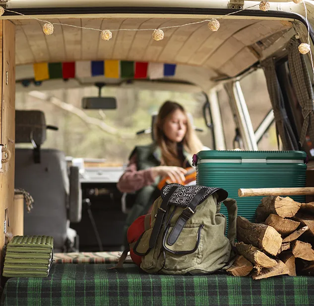 femme dans camper van avec sac a dos et bois