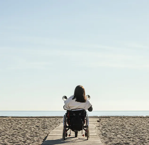 woman in wooden walkway leading to the water of a beach